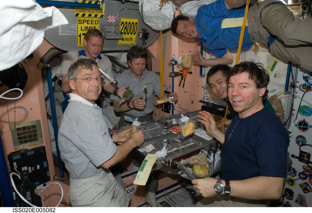 The crew of ISS Expedition 20 share a meal in space.